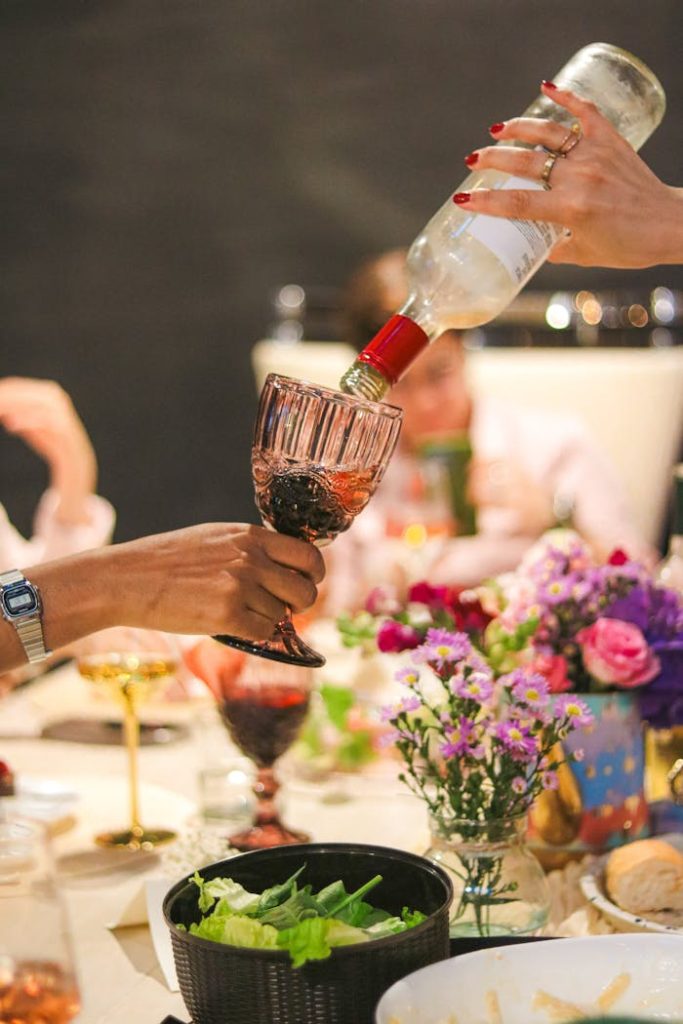 A vibrant dinner scene with wine pouring and floral arrangements.